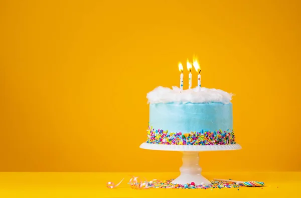 Голубой пирог с тремя свечами на желтом фоне — стоковое фото