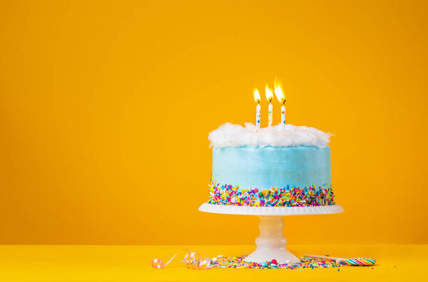 Голубой пирог с тремя свечами на желтом фоне