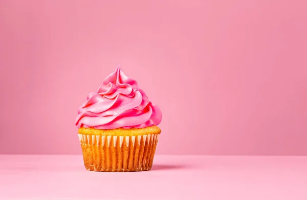 Cupcake rosa con glaseado de crema de mantequilla sobre un fondo rosa. — Foto de Stock