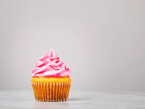 Vanille Cupcake met roze Buttercream Icing op grijs. — Stockfoto