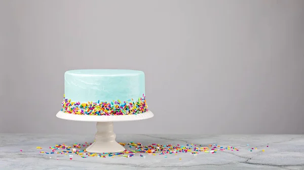 Torta blu con spruzzi colorati su uno stand bianco — Foto Stock