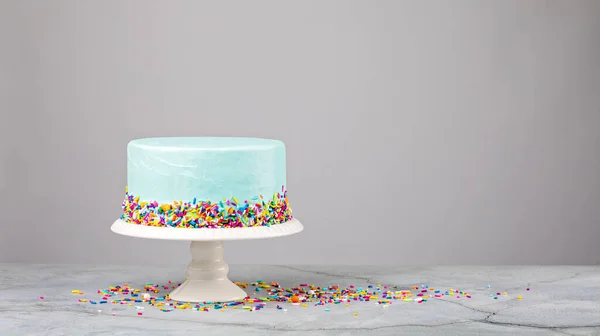 Torta blu con spruzzi colorati su uno stand bianco Immagine Stock