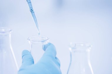 Doktor ya da bilim adamı pipeti kullanarak tıbbi araştırma laboratuarına ya da bilim laboratuarına test tüpü bırakıyor.