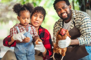 Afrikalı karı koca portresi çocuklara çiftlikte tavuk yetiştirmeyi öğretiyor.