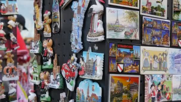 10 października 2021 - Strasburg, Francja: Duża liczba turystycznych magnesów pamiątkowych przedstawiających zabytki miasta i różne symbole. Sklep z pamiątkami ze stoiskiem z magnesami lodówkowymi — Wideo stockowe