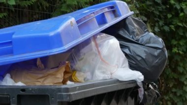 Sokakta içi çöp dolu mavi çöp tenekesi. Çevre kirliliği sorunu