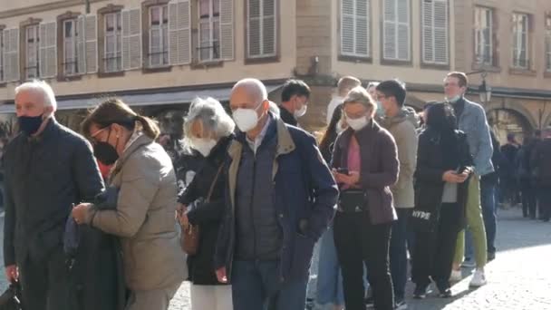 10 жовтня 2021 - Страсбург, Франція: натовп людей різного віку від молодих до старих в захисних медичних масках стоять у черзі. Відстань проти COVID-19 — стокове відео