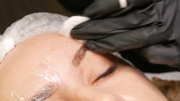 De wenkbrauwvormcorrectie master brengt een speciaal donker pigment onder de huid aan om de dichtheid van de wenkbrauwen te benadrukken. Moderne cosmetische ingrepen, wenkbrauw microblading, permanente make-up, tatoeage — Stockvideo