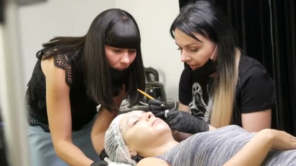 El maestro de micropatinaje enseña a su alumno a hacer la forma correcta de las cejas en el modelo. Maquillaje permanente, tatuaje, cambiar la nueva forma de las cejas — Vídeo de stock