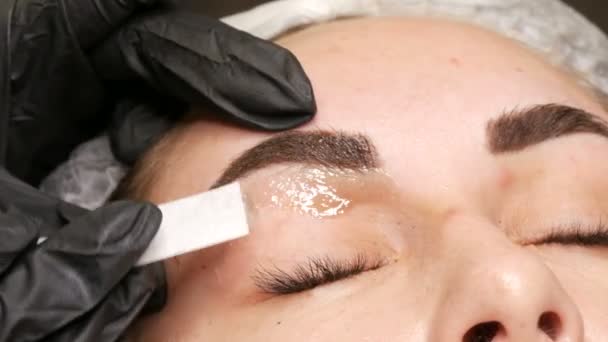 Removal of unnecessary, excess hairs on face. Eyebrow correction using warm wax at the beautician — Stock Video
