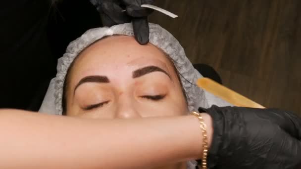 Correction of a beautiful aesthetic shape of eyebrows with hot wax and special tweezers. Removing unnecessary hair from the face. — Stock Video