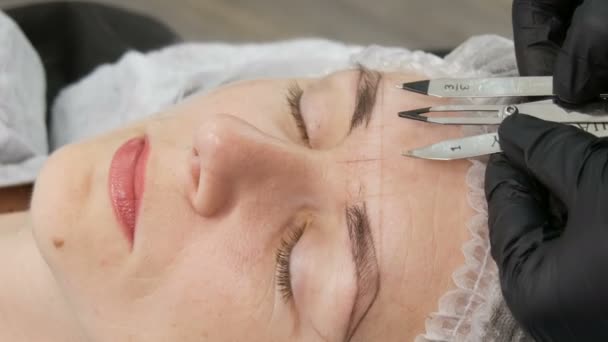 September 7, 2019 - Kamenskoye, Ukraine: A beautiful girl measures the shape of her eyebrows using a special divider or compass. Microblading eyebrows in beauty studio. — Stock Video