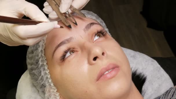 7. September 2019 - Kamenskoye, Ukraine: Ein schönes Mädchen misst die Form ihrer Augenbrauen mit einem speziellen Trennsteg oder Kompass. Microblading Augenbrauen im Schönheitsstudio. — Stockvideo