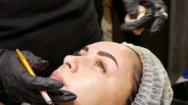 Kaş şekli düzeltme ustası kaşların yoğunluğunu vurgulamak için derinin altına özel koyu bir pigment uygular. Modern kozmetik prosedürleri, kaş mikro pateni, kalıcı makyaj, dövme.