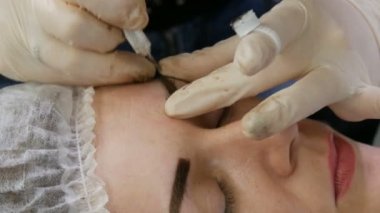 Kaş şekli düzeltme ustası kaşların yoğunluğunu vurgulamak için derinin altına özel koyu bir pigment uygular. Modern kozmetik prosedürleri, kaş mikro pateni, kalıcı makyaj, dövme.