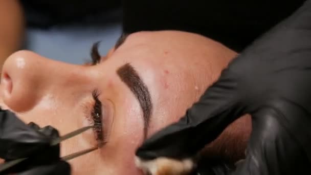 Correction of a beautiful aesthetic shape of eyebrows with hot wax and special tweezers. Removing unnecessary hair from the face. — Stock Video