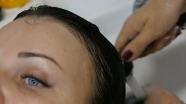 Kuaförde saç yıkama. Yıkanmak için özel lavabo ve duş. Genç, güzel, mavi gözlü, siyah saçlı bir kadın kuaförde saçlarını yıkıyor.