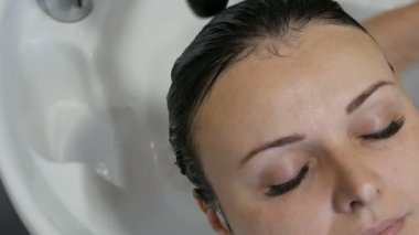 Kuaförde saç yıkama. Yıkanmak için özel lavabo ve duş. Genç, güzel, mavi gözlü, siyah saçlı bir kadın kuaförde saçlarını yıkıyor.