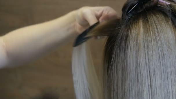 Anpassning av hårlockar med en speciell varm strykning. Blont långt hår av en ung kvinna — Stockvideo