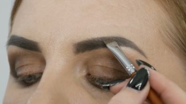 Profesyonel akşam makyajı, özel bir fırça kaş şeklini değiştirir. Makyöz, genç bir kadın mankene kaş çizer.