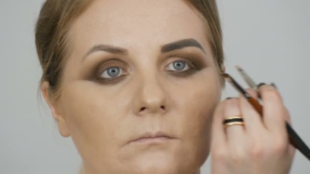 Half a make-up face eyes in a special professional makeup smoky eye. Makeup artist with special brushes and cosmetics makes makeup — Stock Video