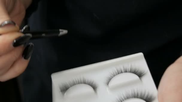 Maquiagem artista leva com fórceps especial falso preto longo grandes pestanas artificiais macias em uma caixa especial com um artista de maquiagem profissional. — Vídeo de Stock