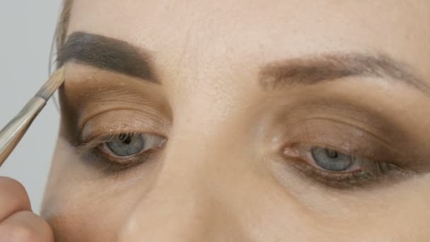 Professionelles Abend-Make-up, ein spezieller Pinsel verändert die Form der Augenbrauen. Maskenbildnerin zieht Augenbrauen vor junges Frauenmodel — Stockvideo