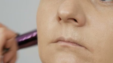 Profesyonel akşam makyajı. Makyöz, genç bir kadın modelin yüz ve boyun vücuduna temel fırçası sürüyor. Kozmetik kavramı.