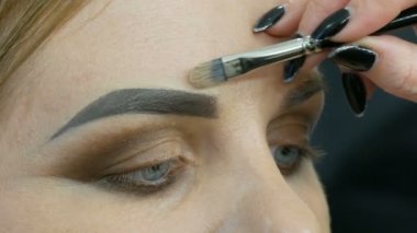 Profesyonel akşam makyajı, özel bir fırça kaş şeklini değiştirir. Makyöz, genç bir kadın mankene kaş çizer.