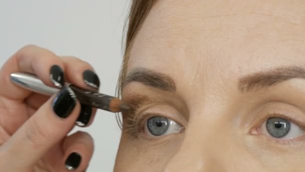 Truccatore professionista fa trucco beige con una matita speciale per una giovane donna modello con gli occhi blu. Sera trucco occhi fumosi luminoso — Video Stock