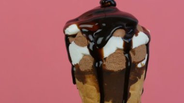 Çikolata sosu buzlanma pembe arka planda bir waffle fincan dondurma üzerinde akar