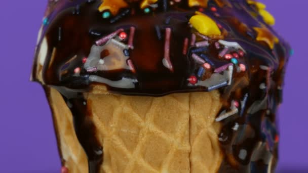 Vanilla ice cream decorated on the top with colorful sprinkles on light purple background . Chocolate sauce icing flows — Stock Video