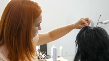 Kadın kuaför stilisti saç stili yapar. Saç spreyini sprey şişeye koymak için özel cila. Güzellik ve moda konsepti. Siyah saçlı..