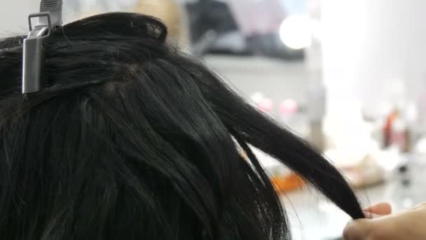 Női fodrász fésülködik hosszú fekete fürtök egy fésűvel. Fodrász fésülködés haj közben fodrász a szépségszalonban. Csinálj frizurát a hosszú hajú nőnek. Szépségkoncepció — Stock videók