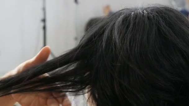 Női fodrász fésülködik hosszú fekete fürtök egy fésűvel. Fodrász fésülködés haj közben fodrász a szépségszalonban. Csinálj frizurát a hosszú hajú nőnek. Szépségkoncepció — Stock videók