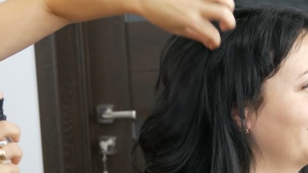 Donna parrucchiere parrucchiere fa acconciatura. Vernice speciale per fissare i capelli in un flacone spray. Concetto di bellezza e moda. Capelli neri. — Video Stock