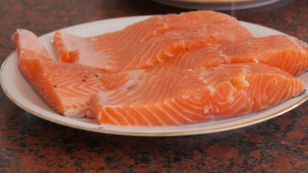 Obrovský filet z červeného lososa nakrájeného na kousky soleného na talíř — Stock video