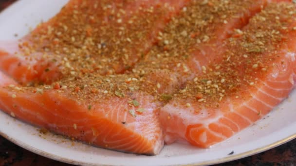 Fillet besar ikan merah salmon dipotong-potong ditaburi dengan bumbu merica di atas piring — Stok Video
