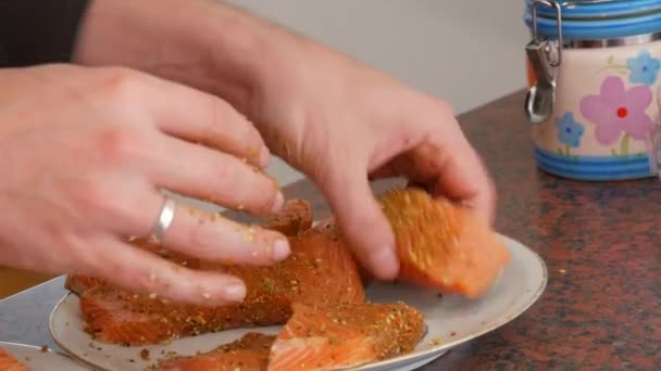 Muž ruce vzít Obrovský filet z červených ryb lososa nakrájené na kousky posypané pepřem koření na talíři — Stock video