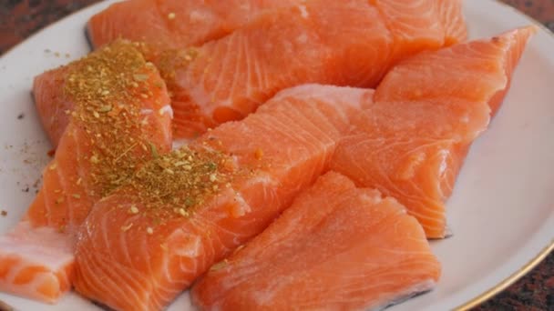 Fillet besar ikan merah salmon dipotong-potong ditaburi dengan bumbu merica di atas piring — Stok Video