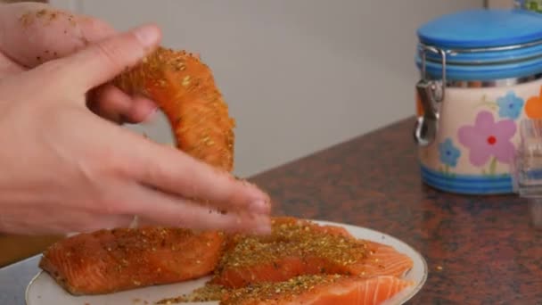 Człowiek ręce wziąć ogromny filet z łososia czerwonej ryby pokroić na kawałki posypać z pieprzem przyprawy na talerzu — Wideo stockowe