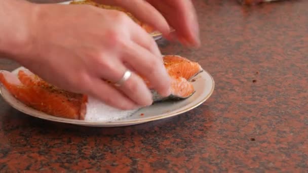 Man hands take Huge fillet of red fish salmon cut into pieces sprinkle with peppercorn seasoning on a plate — Stock Video