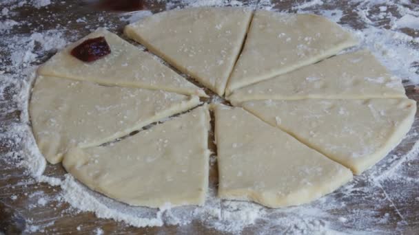 Ženské ruce ležely s lžičkou v kruhu plátky třešňové marmelády na syrovém těstě pro budoucí croissanty. Domácí sladké pečivo. Džem, těsto, dělané ženskou rukou v kuchyni — Stock video