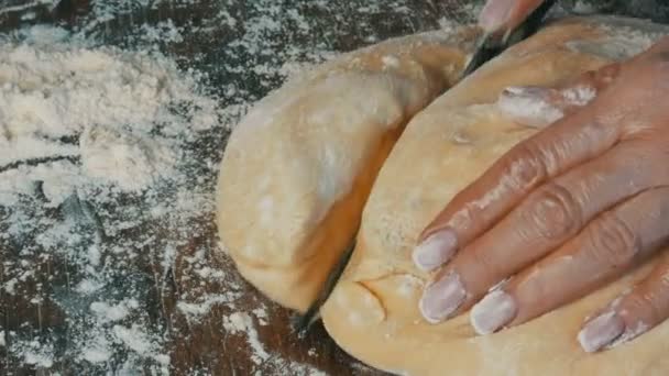 Женская рука режет тесто ножом. Домашняя выпечка на домашней кухне — стоковое видео