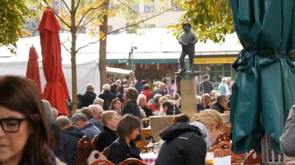 Munique, Alemanha - 24 de outubro de 2019: Pessoas não identificadas no famoso Viktualienmarkt. O famoso Biergarten de Munique no qual as pessoas relaxam. Turistas sentam-se à mesa no parque, bebem cerveja e comem — Vídeo de Stock