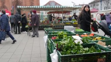 Kehl, Almanya - 19 Kasım 2021: İnsanlar bakkal pazarında dolaşıp, ürünlerini şehir kilisesinin arka planına karşı seçiyorlar