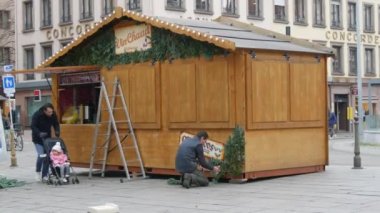 STRASBOURG, FRANCE - 22, 2021: Noel pazarına hazırlanıyor. Bir adam ahşap bir büfeyi köknar dallarıyla süslüyor.
