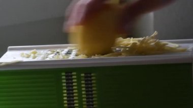 Erkek elleri vejetaryen yemek pişirmek için mutfak rendesine patates sürüyor.