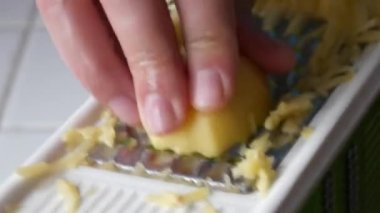 Erkek eller, vejetaryen yemekleri için mutfak rendesine patates sürterek yakından bakıyorlar.