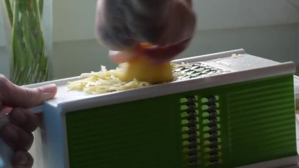 Mannelijke handen wrijven aardappelen op een keukenrasp voor vegetarisch voedsel koken — Stockvideo